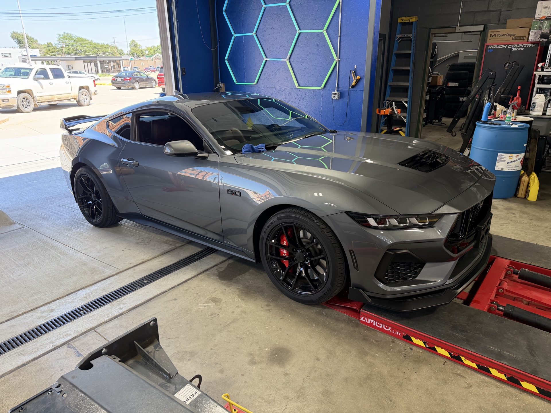 Gray Ford Mustang showing a glossy ceramic-coated finish inside the detailing bay