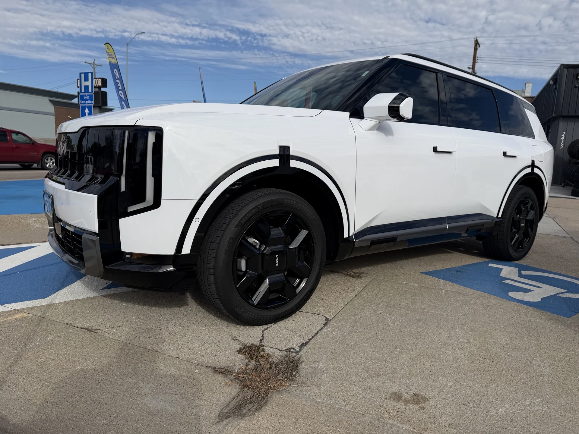 White Kia Telluride with black wheels photographed outside Complete Automotive and Tires after ceramic coating