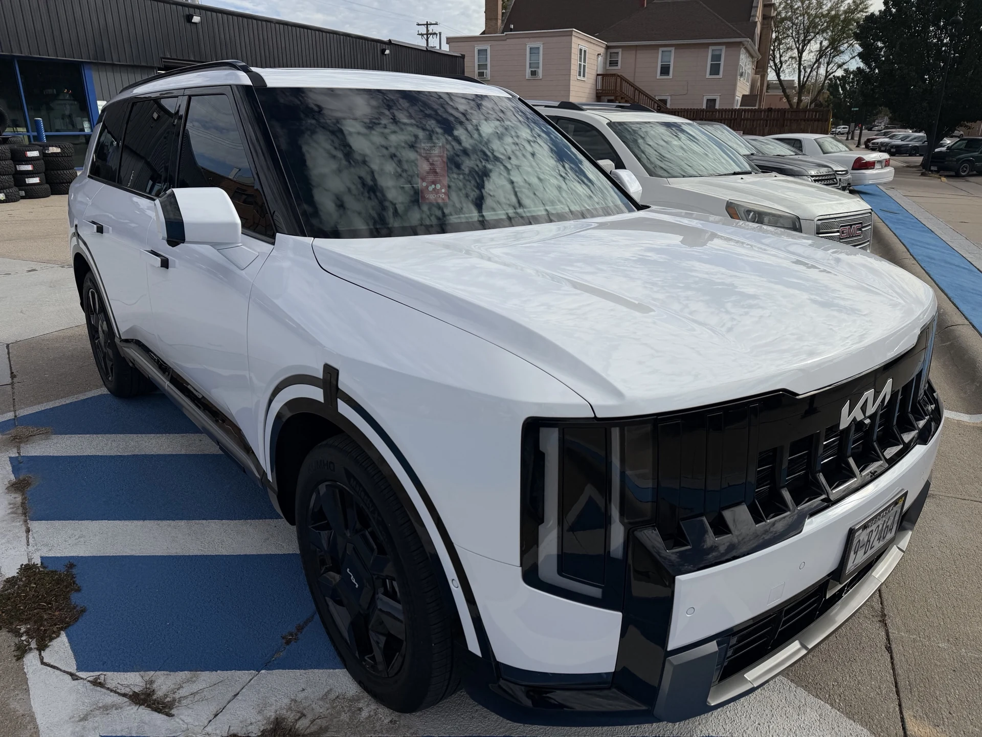 Front three-quarter view of the white Kia Telluride showing sky reflections across its ceramic-coated hood