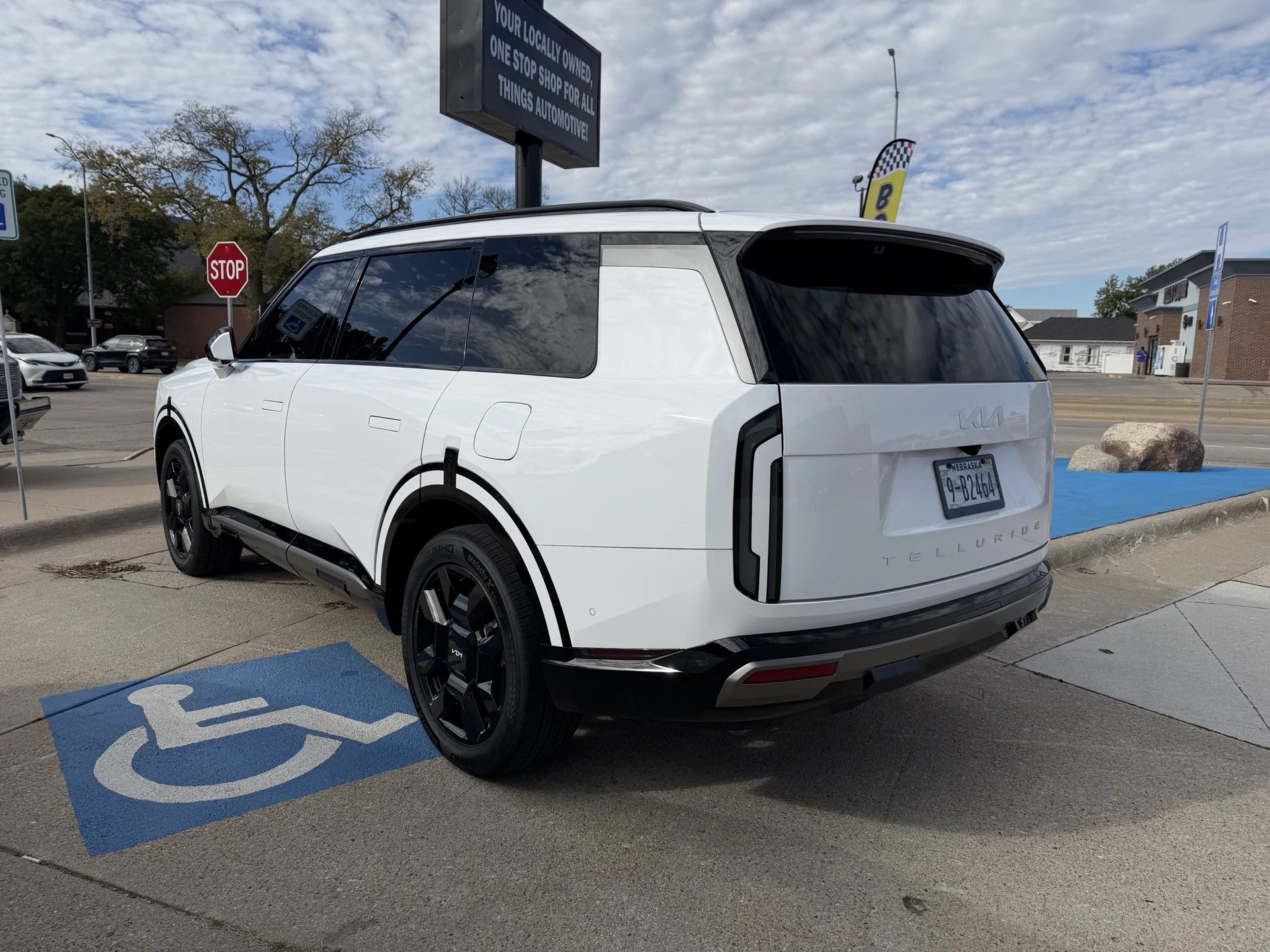 Opposite rear three-quarter view of the white Kia Telluride with sky reflections on its ceramic-coated finish