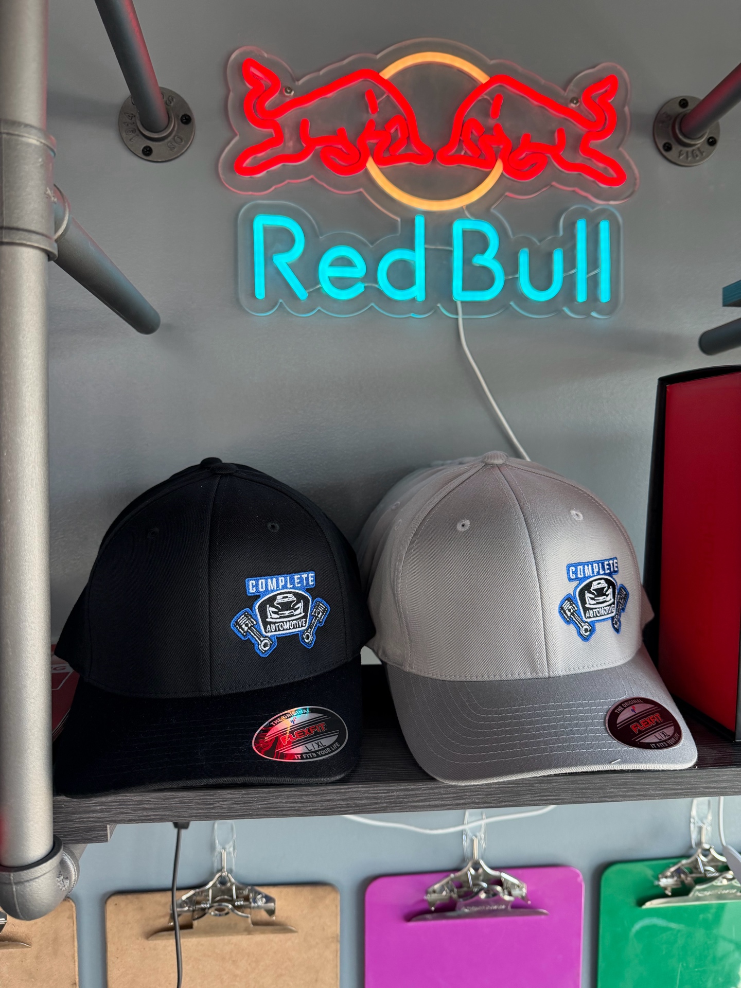 Black and gray Complete Automotive and Tires fitted hats displayed at the shop