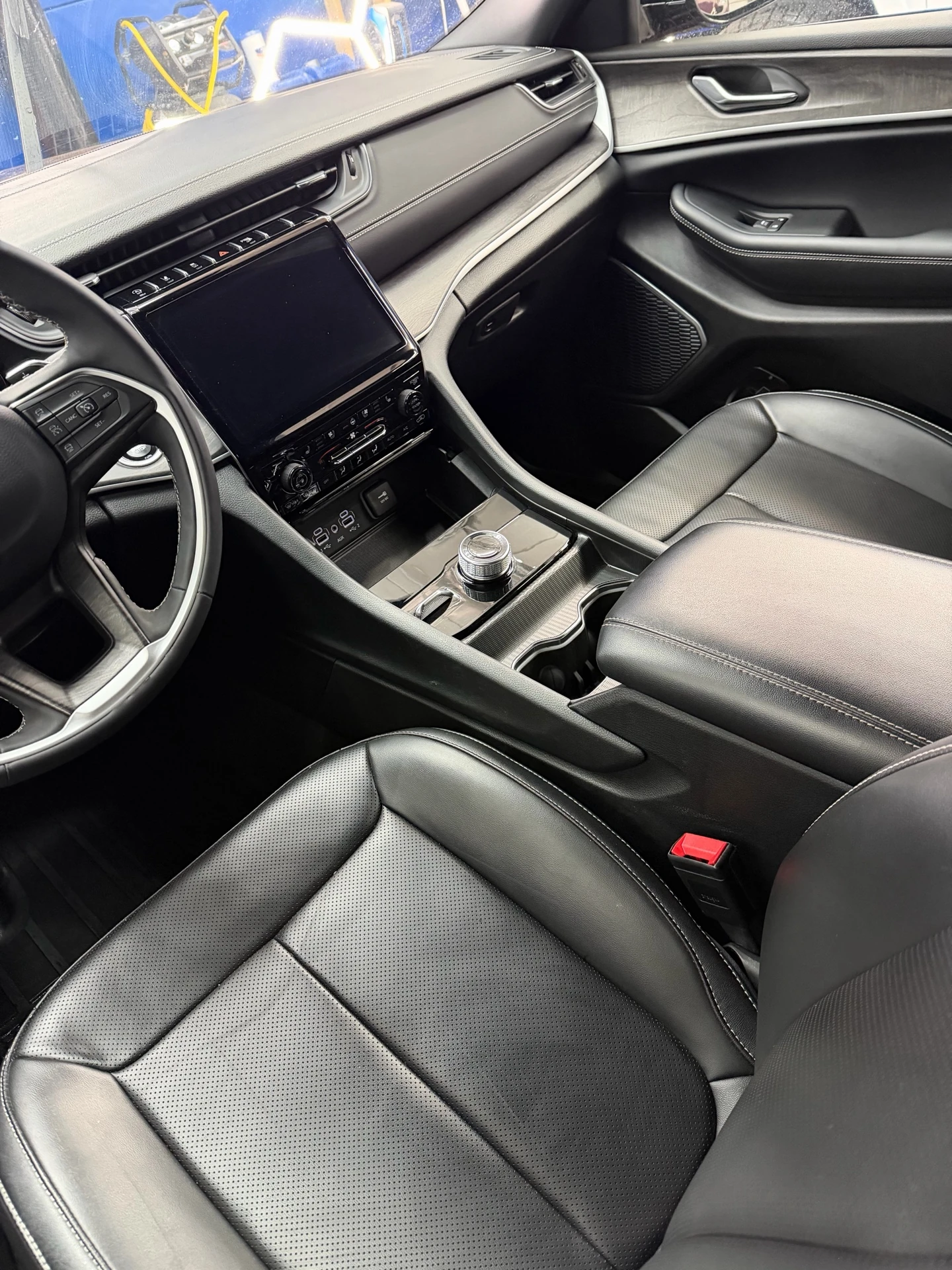 Jeep front cabin showing black leather seats, dashboard, center console and passenger door trim