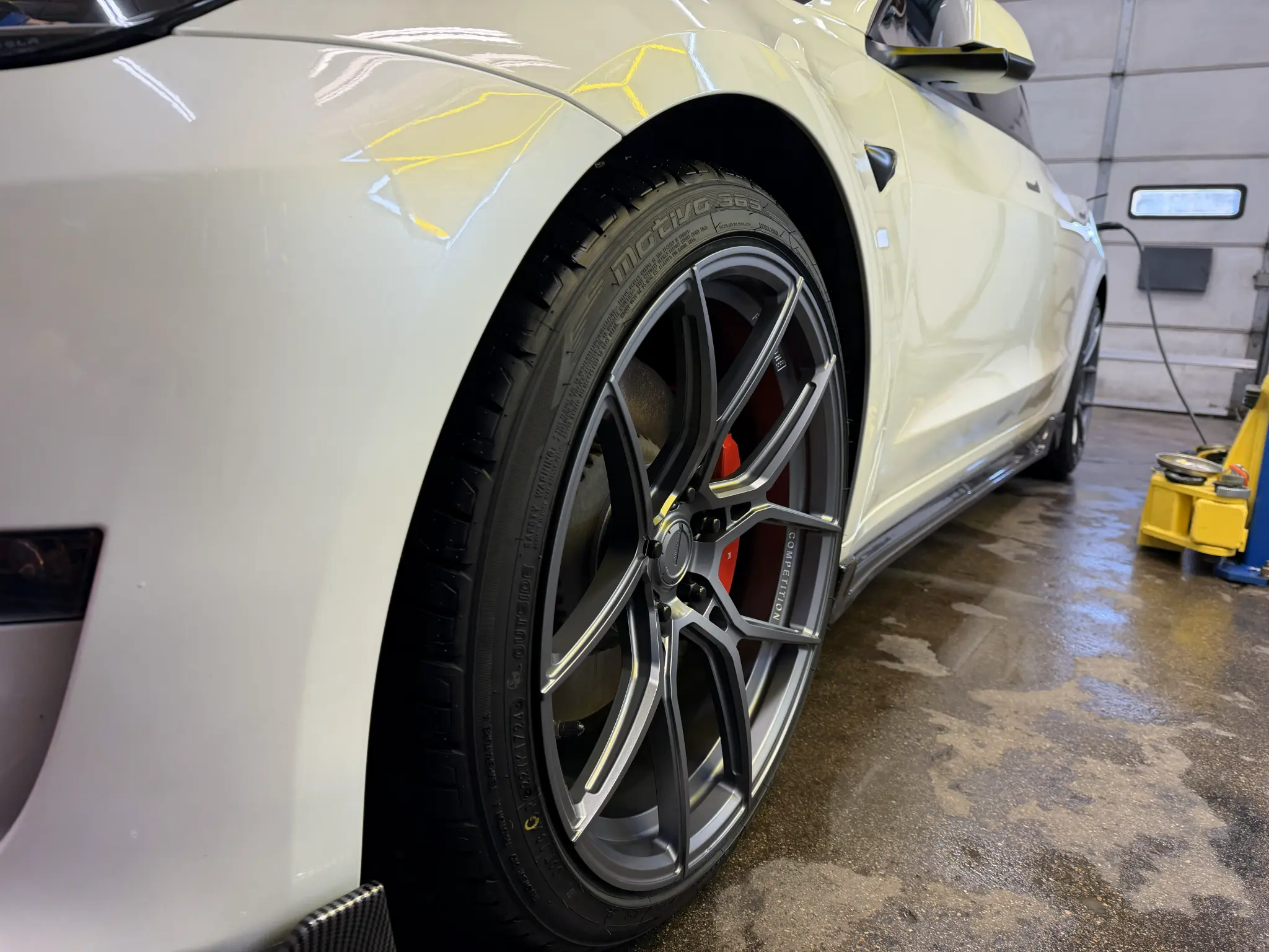 Close-up of a clean gray performance wheel on a white vehicle after detailing