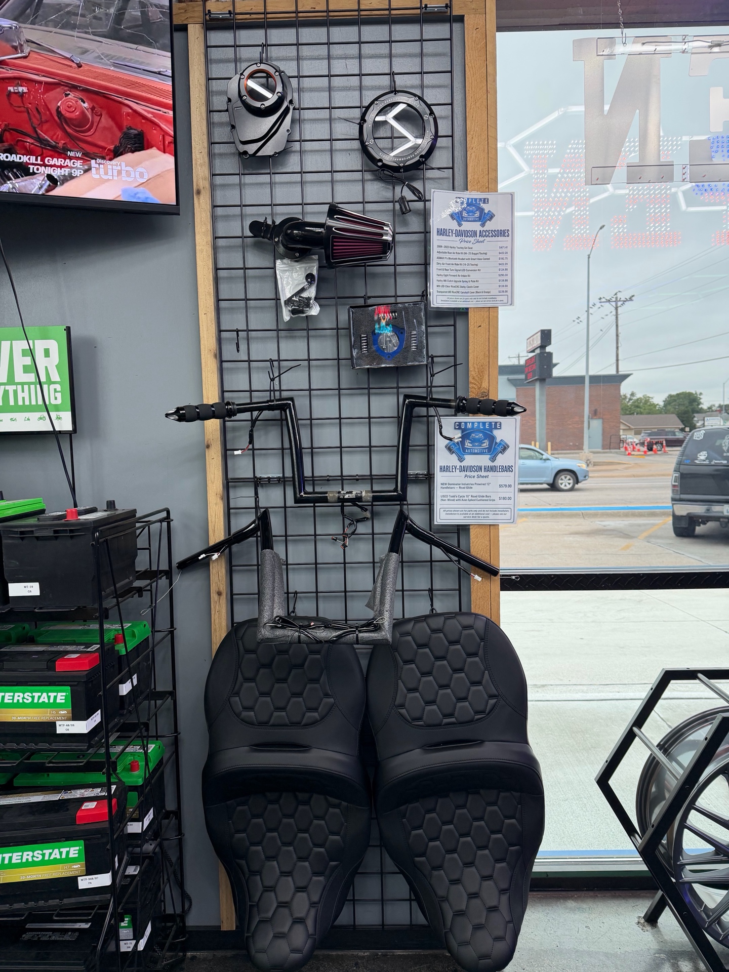 Motorcycle seats, handlebars, and accessories displayed inside Complete Automotive and Tires